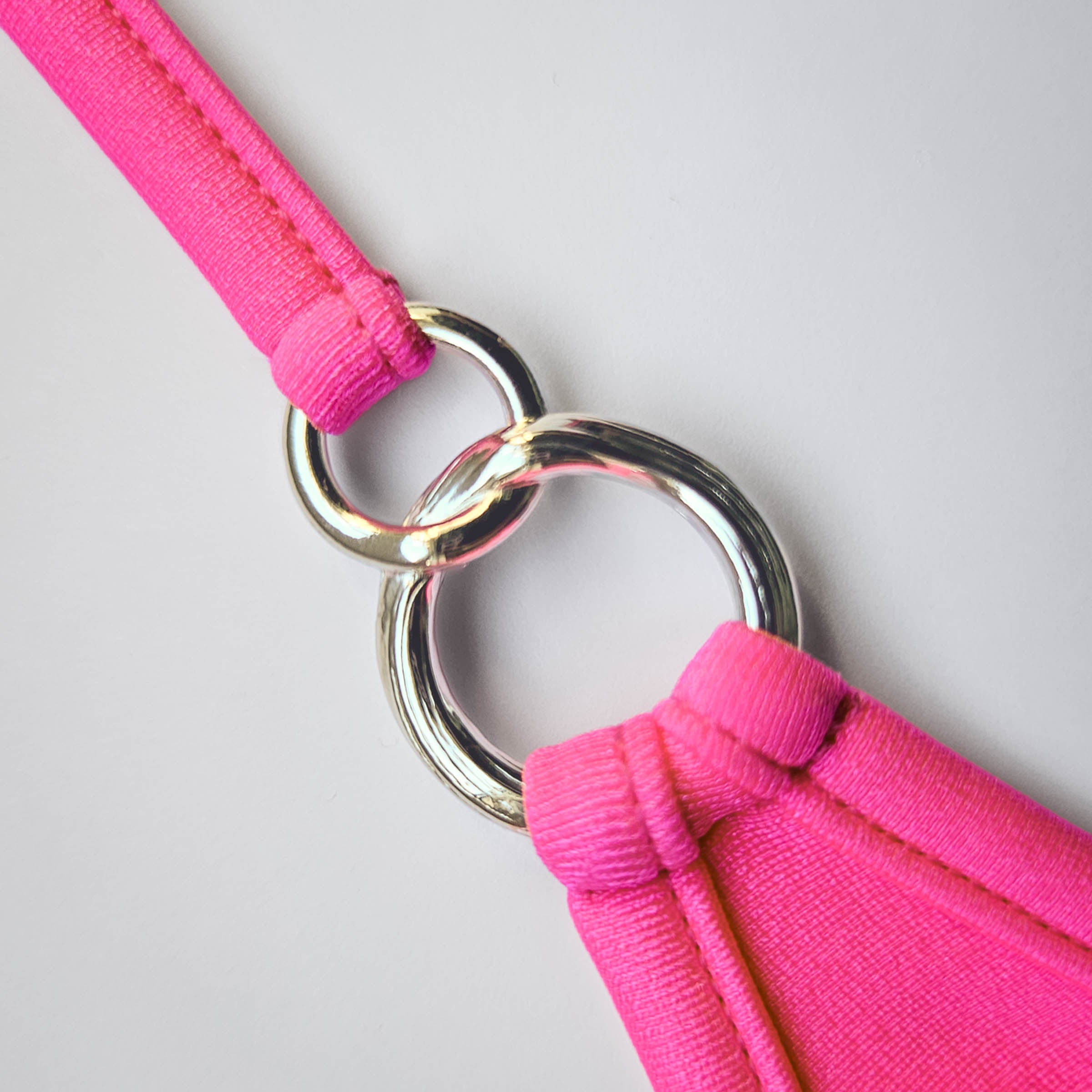 neon pinker Badestoff mit silbernen ineinander verschlungenen Ringen- Neon pink swim fabric with interlinked silver rings