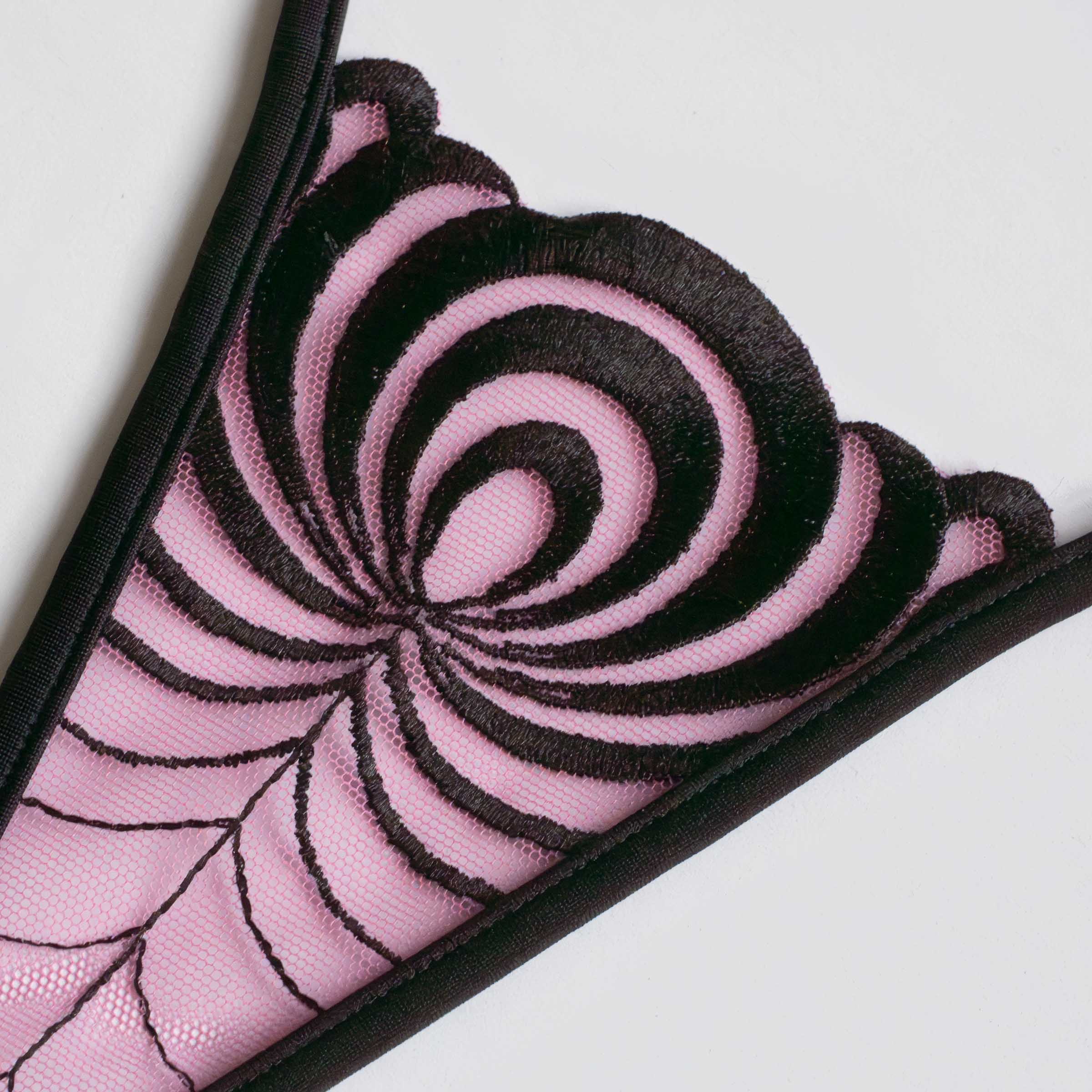 Close-up: black embroidery auf transparentem pinkem Mesh, hypnotic pattern, delicate luxury lingerie